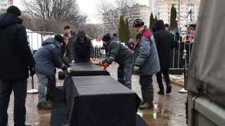 Работники кладбища готовят тележку для гроба.