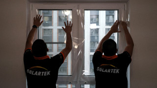 Рабочие устанавливают ударопрочную пленку на окно квартиры в Москве
