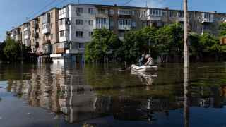 Украинские силовики перевозят местных жителей на лодке во время эвакуации из зоны затопления в Херсоне в 7 июня